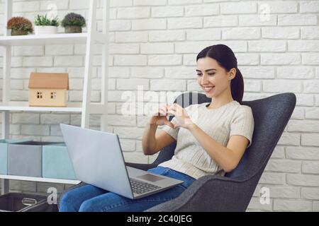 Junge Brünette chatten online, so dass Herd Zeichen. Seitenansicht der Videoanrufankommunikation. Stockfoto