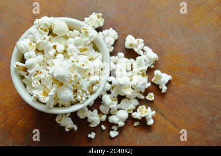 Salziges Popcorn in Tasse auf Holztisch Stockfoto