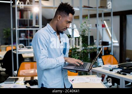 Professionelle konzentriert afrikanischen schwarzen Mann im Büro mit Laptop-Computer, mit Geschäftsanruf mit Kunden. Männliche Ökonomen sucht erforderlich Stockfoto