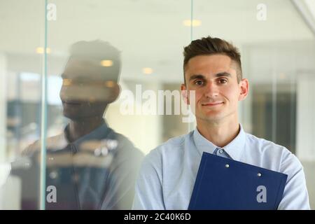 Gut aussehender junger Mann, der an einer Glaswand steht Stockfoto