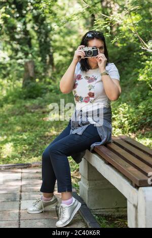 Frau, die im Park mit Kopierplatz fotografiert. Schöne Frau touristischen Fotografen mit Vintage-Kamera. lady Fotograf, weiblich Portrait. Stockfoto