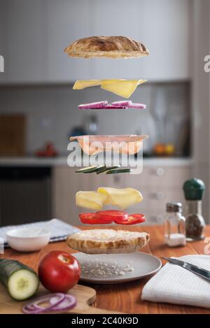 Leviating Sandwich mit seinen Zutaten. Dekonstruierte Sandwichschichten in der Küche Stockfoto