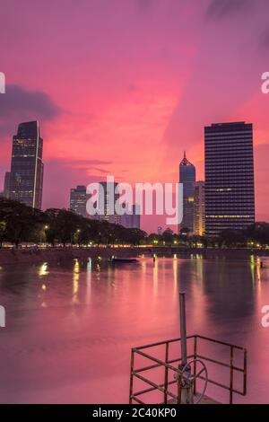 Wunderschöne Sonnenuntergangsszenerie über einem Stausee im Zentrum von Jakarta mit Bürogebäuden und Geschäftszentren im Hintergrund, Jakarta, Indonesien Stockfoto