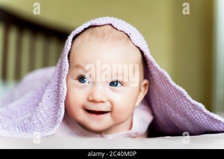 Ein schönes neugeborenes blauäugiges Mädchen liegt auf ihrem Bauch und lächelt Stockfoto