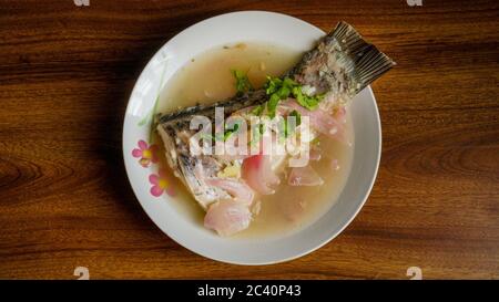 Gedünsteter Rohu-Fisch in Zitronensauce mit roter Zwiebel und garniert mit Koriander. Stockfoto