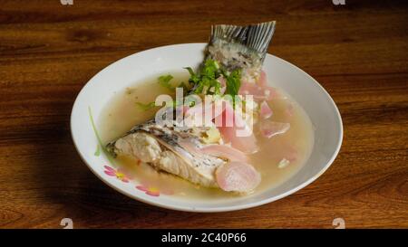 Gedünsteter Rohu-Fisch in Zitronensauce mit roter Zwiebel und garniert mit Koriander. Stockfoto