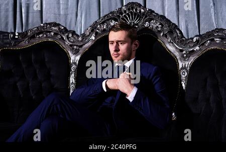 Geschäftsmann mit durchdachtes, ernsthaftes Gesicht in klassischer Einrichtung. Der kriminelle Boss im Luxusanzug sitzt auf dem Vintage-Sofa. Reicher Mann mit Bart. Erfolg, Kriminalität, Mafia, Gangster Konzept. Retro-Style, Mode. Stockfoto