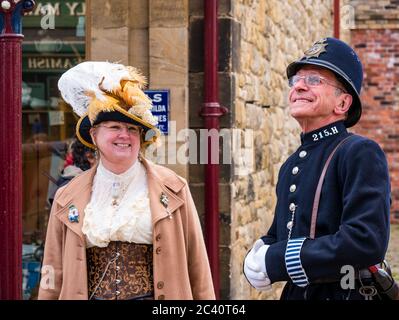 Menschen in historischen Kostümen mit Mann in altmodischer Polizeiuniform und Frau mit gefiedertem Hut, Beamish Museum, Durham County, England, Großbritannien Stockfoto