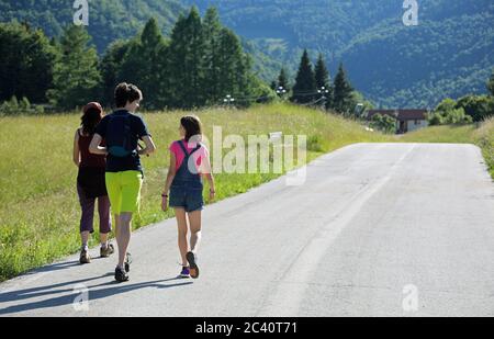 Mutter mit zwei kleinen Kindern beim Spaziergang auf der Asphaltstraße Stockfoto