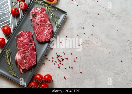 Zwei frische rohe Fleischsteaks auf schwarzer Keramikplatte Stockfoto