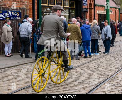 Mann, der mit einem Boneshaker-Vintage-Fahrrad in einem historischen Kostüm reitet, Beamish Museum, Durham County, England, Großbritannien Stockfoto