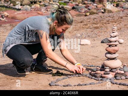 Frau balanciert Steine, European Stone Stacking Championship, Eye Cave Beach, Dunbar, East Lothian, Schottland, Großbritannien Stockfoto