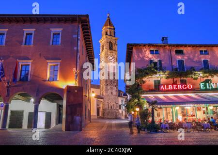 Nachtaufnahme in der Kurstadt Ascona, Tessin, Italien mit dem Glockenturm der Pfarrkirche SS. Piedro und Paolo, hinter der Uferpromenade famii Stockfoto