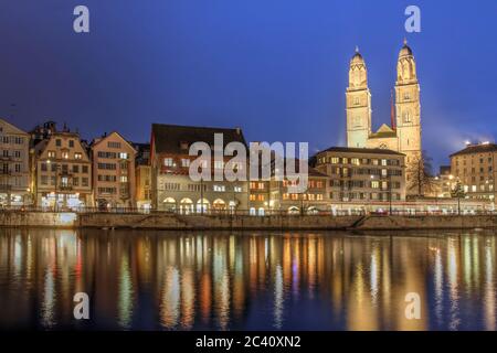 Dämmerungsszene in Zürich, Schweiz, mit der Stadt, die sich im Wasser der Limmat spiegelt, während sie in den Zürichsee fließt. Grossmunster (Toller Mi Stockfoto