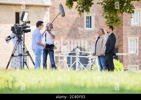 Grevenbroich, Deutschland. Juni 2020. Jan Josef Liefers (r), Schauspieler, (als Karl-Friedrich Boerne) und Axel Prahl, Schauspieler, (als Frank Thiel) geben einem Fernsehteam des WDR ein Interview während der Dreharbeiten zum neuen Tatort aus Münster vor dem Schloss Hülchrath. Ein Sendetermin für den Tatort mit dem Titel "Long Live The King" in der ARD ist noch nicht festgelegt. Quelle: Rolf Vennenbernd/dpa/Alamy Live News Stockfoto