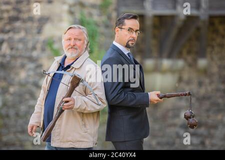 Grevenbroich, Deutschland. Juni 2020. EXKLUSIV - Jan Josef Liefers (r), Schauspieler, (als Karl-Friedrich Boerne) mit Morgenstern mit zwei Metallkugeln und Axel Prahl, Schauspieler, (als Frank Thiel) mit Armbrust, stehen vor Schloss Hülchrath während der Dreharbeiten zum neuen Tatort aus Münster. Ein Sendetermin für den Tatort mit dem Titel "Long Live The King" in der ARD ist noch nicht festgelegt. Quelle: Rolf Vennenbernd/dpa/Alamy Live News Stockfoto