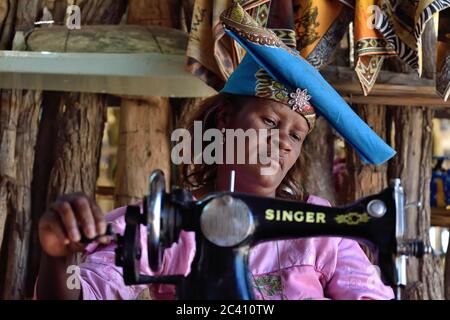 KAOKOLAND, NAMIBIA - 1. FEB 2016: Unbekannte Herero-Frau in traditioneller Kleidung mit Nähmaschine. Die Herero, die zur Bantu Gruppe gehören, mit Stockfoto