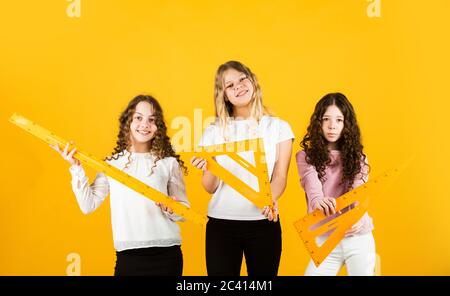 Schüler, die sich auf die Prüfungen vorbereiten. schwesternschaft. Drei Mädchen mit Dreieck und Lineal. Zurück zur Schule. MINT-Schuldisziplinen. Mathematik und Menschen konz Stockfoto