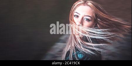 Langhaarige Blondine tanzt im Park voller Freude und Glück, viel Copyspace auf der rechten Seite Stockfoto