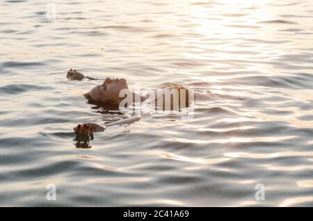 Junge Frau schwimmt auf dem Rücken im Meer Stockfoto