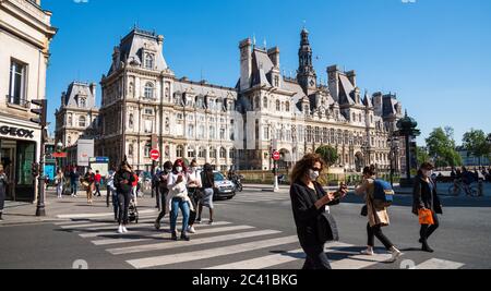 Paris, Frankreich - 15. Mai 2020: Menschen mit Schutzmasken überqueren die Straße in der Nähe des Rathauses, spazieren zum Einkaufen. Leben mit Coronaviren Stockfoto