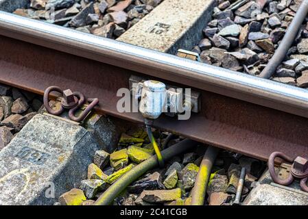 Gleise auf Betonschwellen liegend, große Felsstücke füllend, Nahaufnahme der Achszählerfassungseinheit. Stockfoto