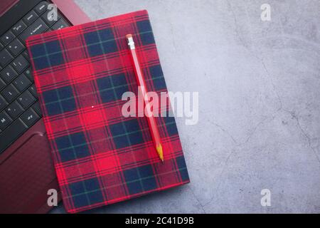 Roter Notizblock, Bleistifte und Laptop auf schwarzem Hintergrund Stockfoto