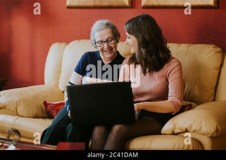 Enkelin zeigt ihrer Großmutter etwas auf dem Laptop Stockfoto