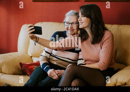 Enkelin und Großmutter machen ein Selfie auf dem Sofa Stockfoto