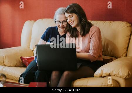 Enkelin zeigt ihrer Großmutter etwas auf dem Laptop Stockfoto