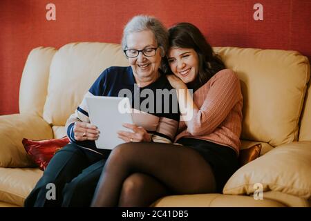 Enkelin und Großmutter beobachten etwas auf dem Tablet Stockfoto