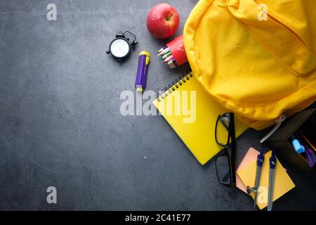 Back to School Konzept mit gelbem Rucksack und Schulbedarf. Stockfoto