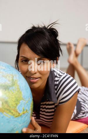 Junge dunkelhaarige Frau hält einen Globus in der Hand - Nationalität - Globalisierung Stockfoto