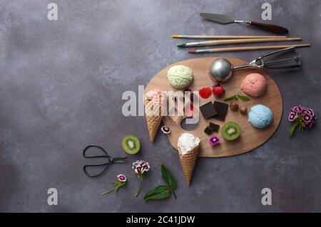 Verschiedene Eiscreme mit Malerpalette und Zutaten in der Mitte, darunter Erdbeere und Minze Stockfoto