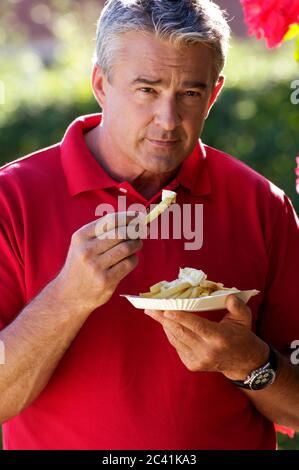 Älterer Mann isst pommes mit Majo Stockfoto