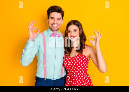 Foto schön hübsche Dame gut aussehend Kerl toothy lächelnd Prom paar zeigt okey Symbole Hände tragen rot gepunktete Kleid Hemd Fliege Retro Kleidung Stockfoto