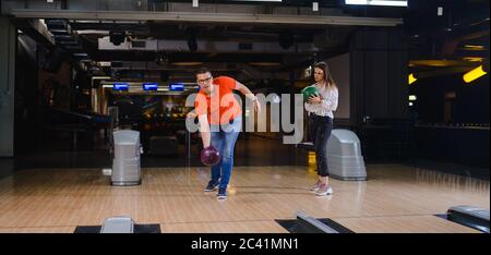 Ein schönes liebend kaukasisches Paar, das Bälle auf der Bowlingbahn wirft. Freund und Freundin im Bowling Club Stockfoto