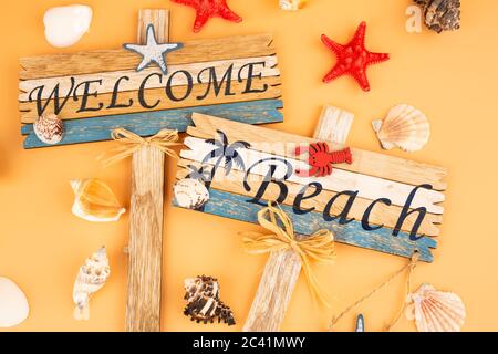 Holzschilder begrüßen Strand, Seesterne und Muscheln auf gelbem Hintergrund. Stockfoto