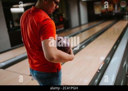 Nahaufnahme der Hand eines kaukasischen Mannes, der einen Ball in einem Bowlingclub hält Stockfoto