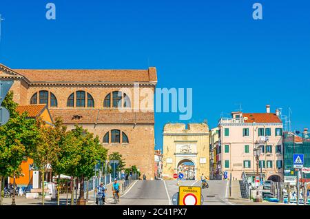 Chioggia, Italien, 16. September 2019: Blick auf die Straße mit Porta Santa Maria o Porta Garibaldi Tor und Kathedrale Santa Maria Assunta Duomo Kirche in der Altstadt, blauer Himmel, Region Venetien Stockfoto