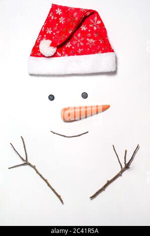 Schneemann Gesicht auf weißem Hintergrund. Ein Satz von Gegenständen für die Herstellung eines Schneemann - ein roter Hut, Karotten, Augen - Tasten, Zweige. Wie man einen Schneemann zu machen. Stockfoto