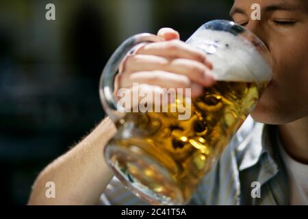 Der junge Mann hält einen Becher mit Bier in der Hand - Sommer - Alkohol - Biergarten Stockfoto