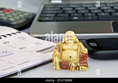 Buddha-Statue vor Bürogeräten, die die Stressreduzierung symbolisieren Stockfoto