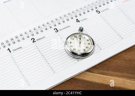 Stoppuhr auf einem Holztisch liegend (mit den Bildunterschriften der Wochentage in Deutsch) Stockfoto