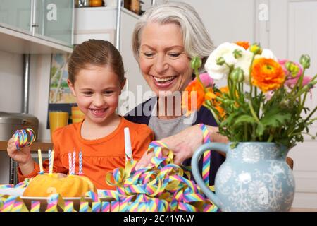 Kleines Mädchen und ihre Oma mit Geburtstagskuchen und Streamer - Zweisamkeit Stockfoto