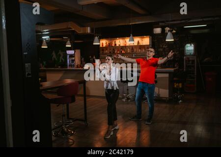 Eine junge schöne kaukasische Frau und ein Mann spielen Darts. Liebe und Erholung Stockfoto