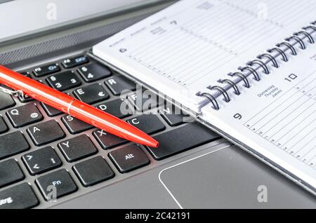 Roter Stift und Zeitplan liegen auf der Computertastatur Stockfoto
