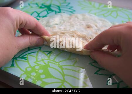 Die Hände der Köchin, die die Frühlingsrollen auf der Theke in ihrer Küche vorbereitet Stockfoto