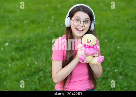 Sommerspiel. Happy Girl spielen mit Teddybär auf grünem Gras. Kindheitsspiele zu spielen. Aktivitäten im Freien. Entwicklung und Wachstum von Kindern. Spielen mit Spielzeug. Spielwarenladen. Spielen Sie, um Phantasie zu entwickeln. Stockfoto