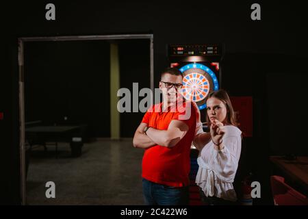 Eine junge schöne kaukasische Frau und ein Mann spielen Darts. Liebe und Erholung Stockfoto